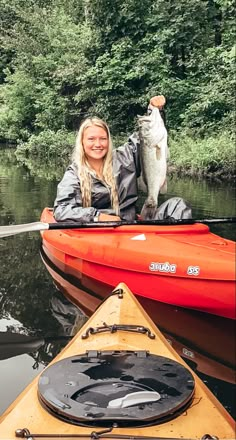 a woman holding a fish while sitting in a kayak