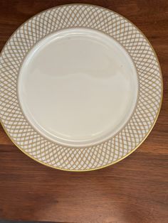 a white and gold plate sitting on top of a wooden table