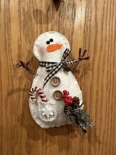 a snowman made out of paper and buttons on a wooden surface with candy canes