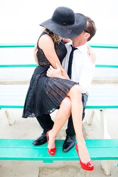 a man and woman sitting on a bench with their arms around each other as they kiss