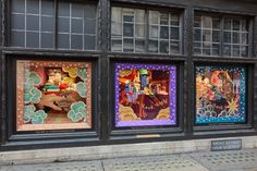 three windows with different designs on them in front of a building