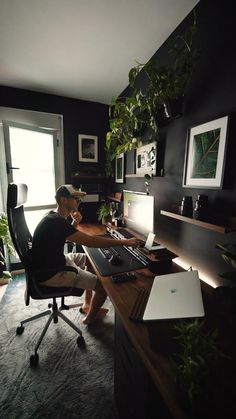 a man sitting at a desk in front of a computer on top of a wooden desk