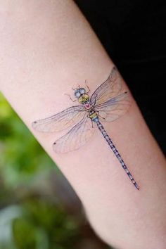 a small dragonfly tattoo on the arm