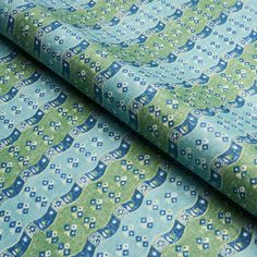 a blue and green patterned fabric with small flowers on it's edges, in the shape of an owl