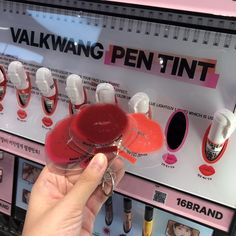 a person is holding up a red cup in front of a vending machine with white cups on it