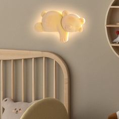 a baby's room with a teddy bear light on the wall