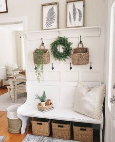 a white bench with baskets and plants on it in front of a wall mounted coat rack