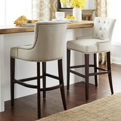 two white bar stools sitting in front of a counter with yellow flowers on it