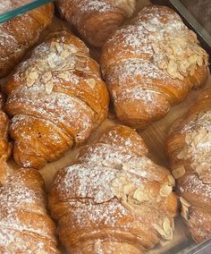 several croissants with powdered sugar on them in a glass container,