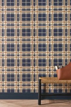 a blue and white plaid wallpaper with a brown leather pillow on top of it