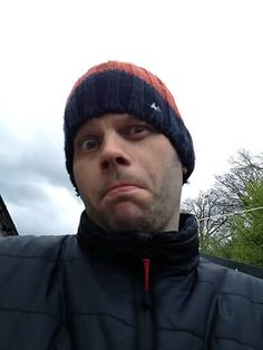 a man wearing a beanie looks at the camera with an angry look on his face