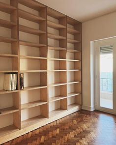 an empty bookcase in the corner of a room with wooden floors and hard wood flooring