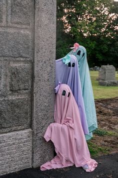 three towels hanging on the side of a stone wall in front of a cemetery with tombstones and trees