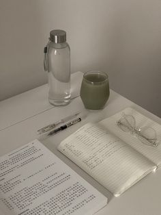 an open notebook, pen and glasses on a table