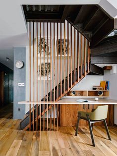 a room with wooden flooring and a stair case next to a white table in front of a staircase