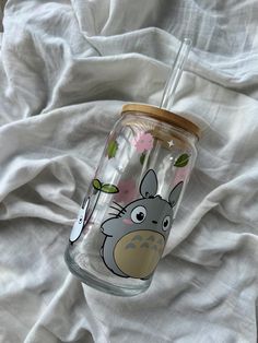 a glass cup with an image of totoro on it sitting on a bed