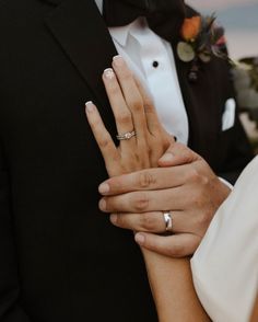 the bride and groom are holding each other's hands with wedding rings on their fingers