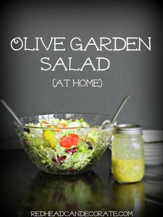 a salad in a glass bowl next to a jar with dressing on it and the words olive garden salad at home