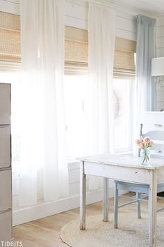 a white table sitting in front of a window next to a refrigerator