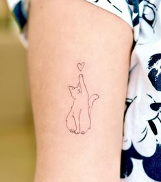 a small cat tattoo on the back of a woman's left arm and leg