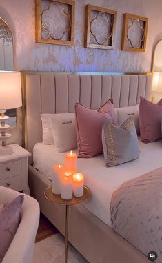 a bed with pillows and candles on it in a room that has two mirrors above the bed