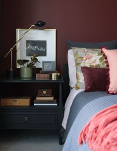 a bed with pillows and some pictures on the wall above it, along with other items