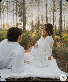 a woman sitting on top of a blanket next to a man