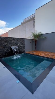 an empty pool in the middle of a backyard with a water feature and wooden decking