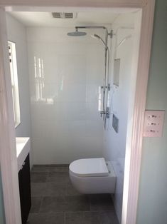 a white toilet sitting in a bathroom next to a sink and shower faucet