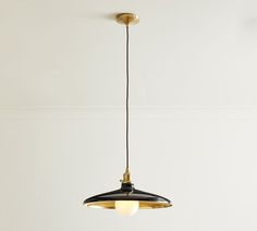 a black and gold pendant light hanging from a ceiling in a room with white walls