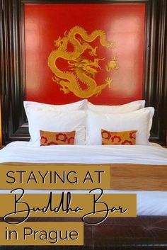 a bed with white sheets and red walls in front of a dragon head on the wall