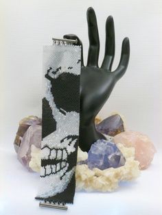 a black and white bracelet with an image of a skull on it next to rocks