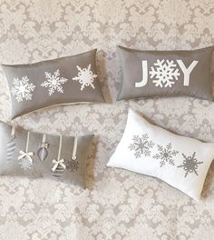 four pillows with snowflakes on them and the word joy written in white