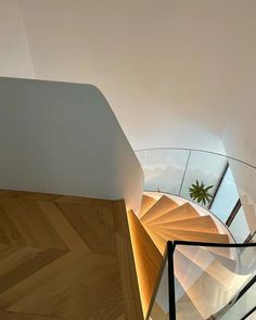 a spiral staircase with glass railing and wooden handrail