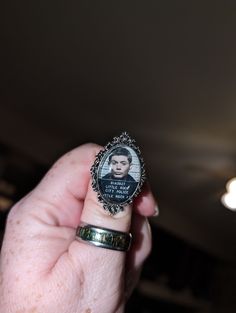 a woman's hand holding a ring with an image of a person on it