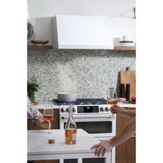 two people standing in a kitchen next to an oven with wine glasses on the counter