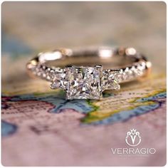 a three stone diamond ring sitting on top of a map