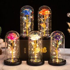 four glass vases with flowers in them on a table