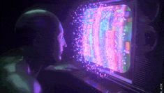 a man sitting in front of a computer monitor with colorful lights on it's screen