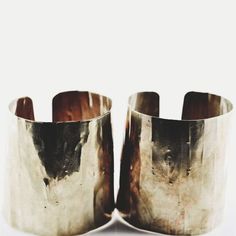 two silver cuff bracelets sitting on top of each other