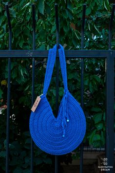 a blue crocheted bag hanging on a fence