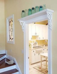 an open door leading to a kitchen with white cabinets and counter tops on top of it