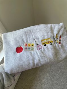 a white pillow with embroidered appliqued items on it sitting on the floor