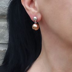 Featuring a unique design, one sphere in radiant silver and the other in warm copper, these earrings effortlessly blend sophistication with a contemporary twist. Let the contrasting metals dance together, creating a stylish and eye-catching accessory. The silver sphere is 6mm and the copper sphere is 10mm. 925 Sterling silver Copper Post back Approx. 0.9" L x 0.5" W Handmade in Taxco, Mexico Modern Copper Jewelry For Pierced Ears, Silver Copper Earrings For Party, Modern Rose Gold Dangle Earrings, Modern Sphere Earrings With Polished Finish, Modern Polished Sphere Earrings, Modern Nickel-free Rose Gold Earrings, Silver Sphere Metal Earrings, Silver Copper Drop Earrings, Metal Round Earrings As Gift