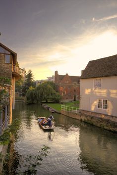 two people are in a small boat on the water next to some buildings and trees