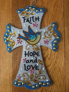 a cross with the words faith and a bird on it is hanging from a wooden floor