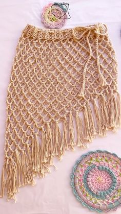 a crocheted shawl and doily on a white tablecloth next to it