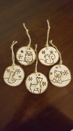 four wooden ornaments are hanging from twine on a table with some string attached to them