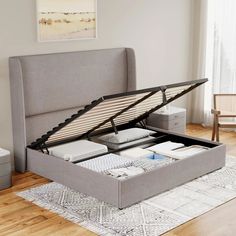 a bed with an open storage compartment on top of it in a living room next to a window