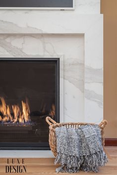 a fireplace with a basket and blanket next to it